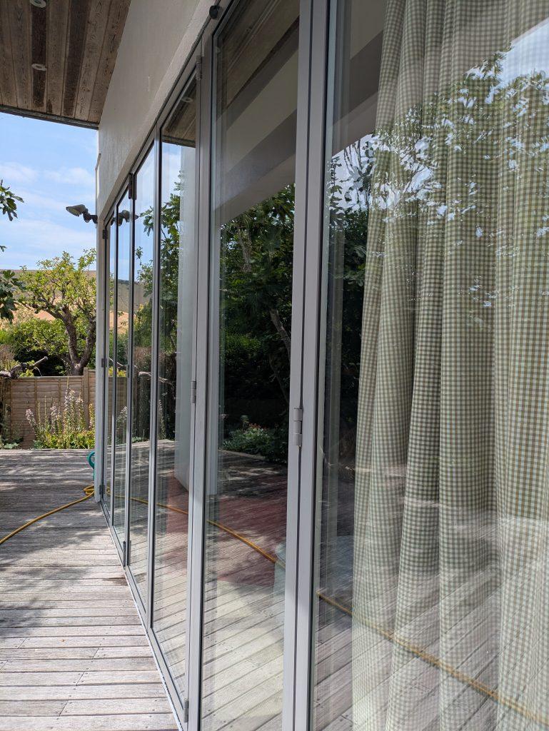 Clean folding glass doors reflecting trees at a modern home near Wadhurst