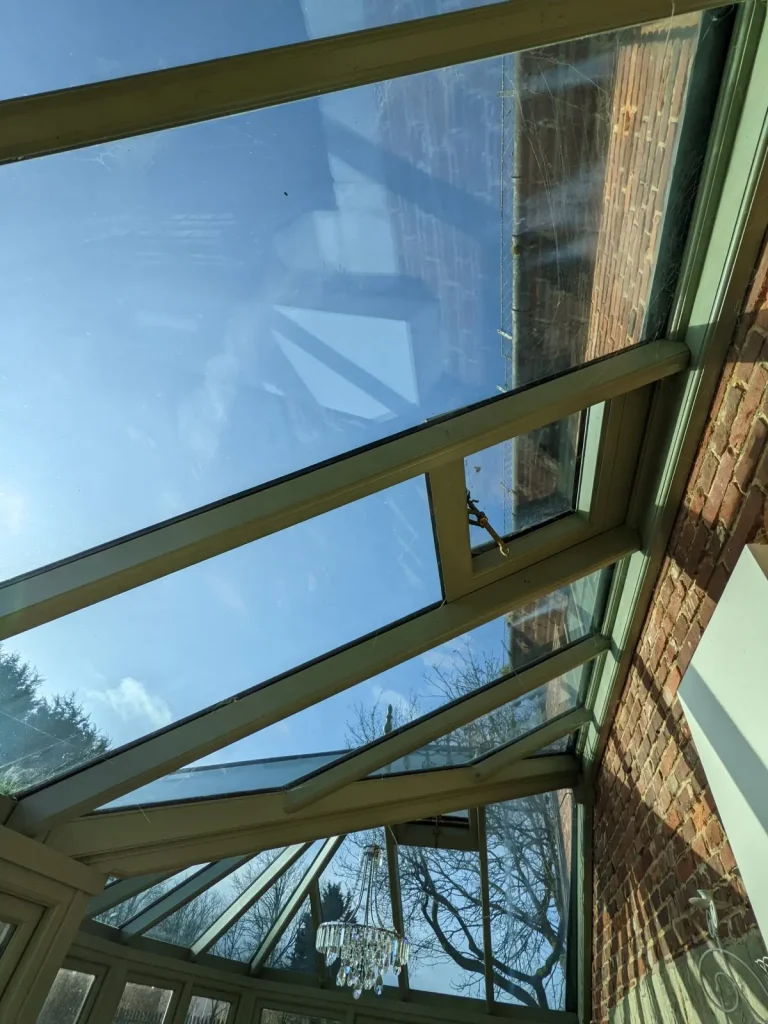 Clean glass roof viewed from inside against a blue sky