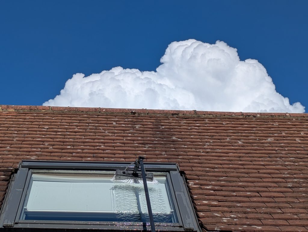 cleaning glass of a roof window with a blue-sky background and cumulous cloud